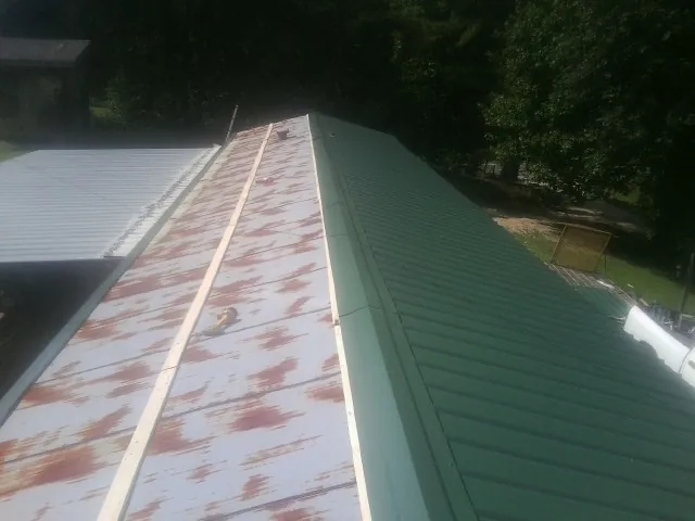 Old rusted panels beside newly installed green metal roofing — Wind Damage Roof Repair by Roofing Brothers in Monrovia
