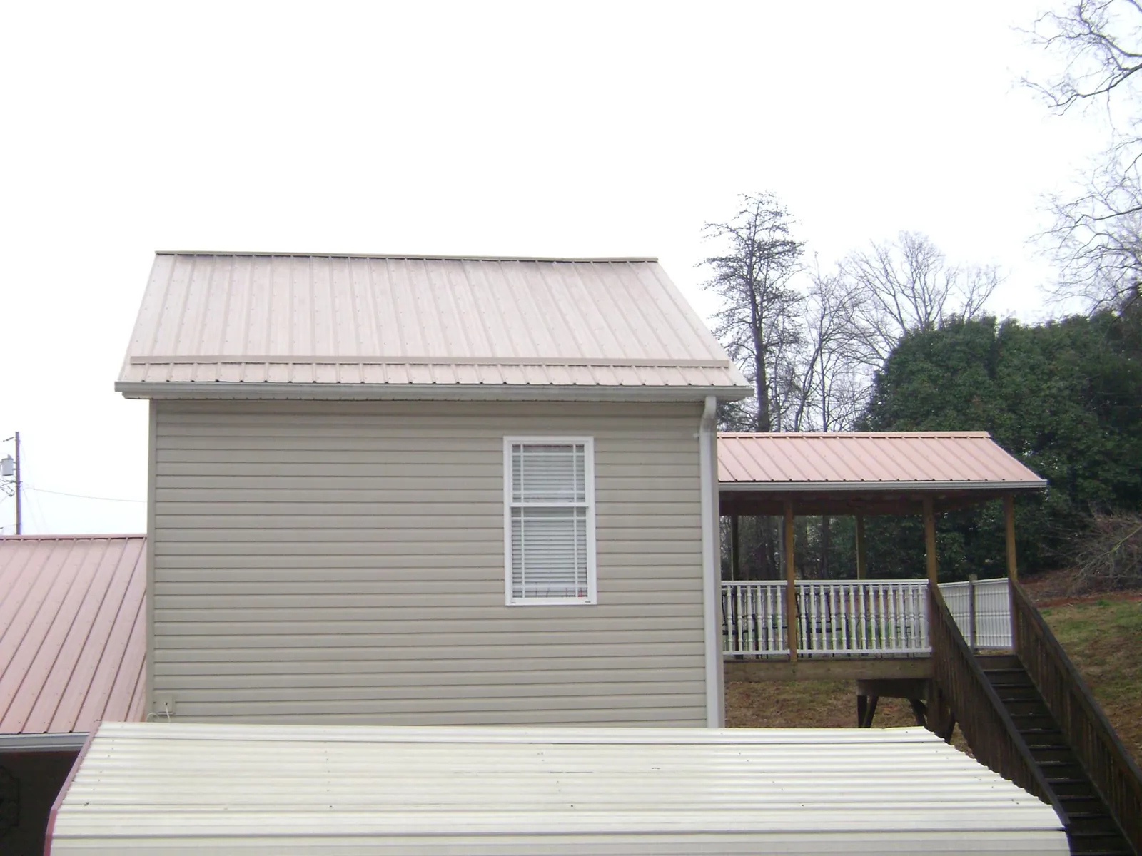 Tan metal roofs on a two story addition and attached porch, from a Roof Replacement job in Monrovia